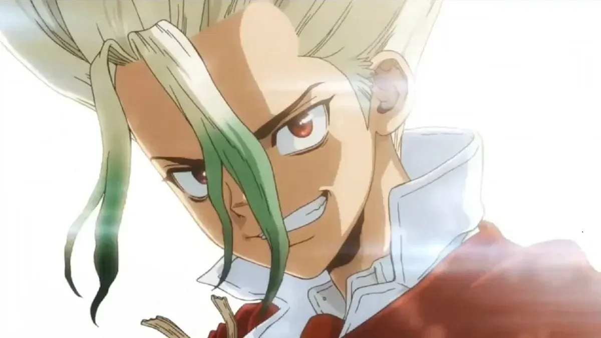 Senku, with spiky pale hair fading to green and a red coat, grins fiercely in a close-up washed with white light, in a still from the final episode of Dr. Stone: Science Future